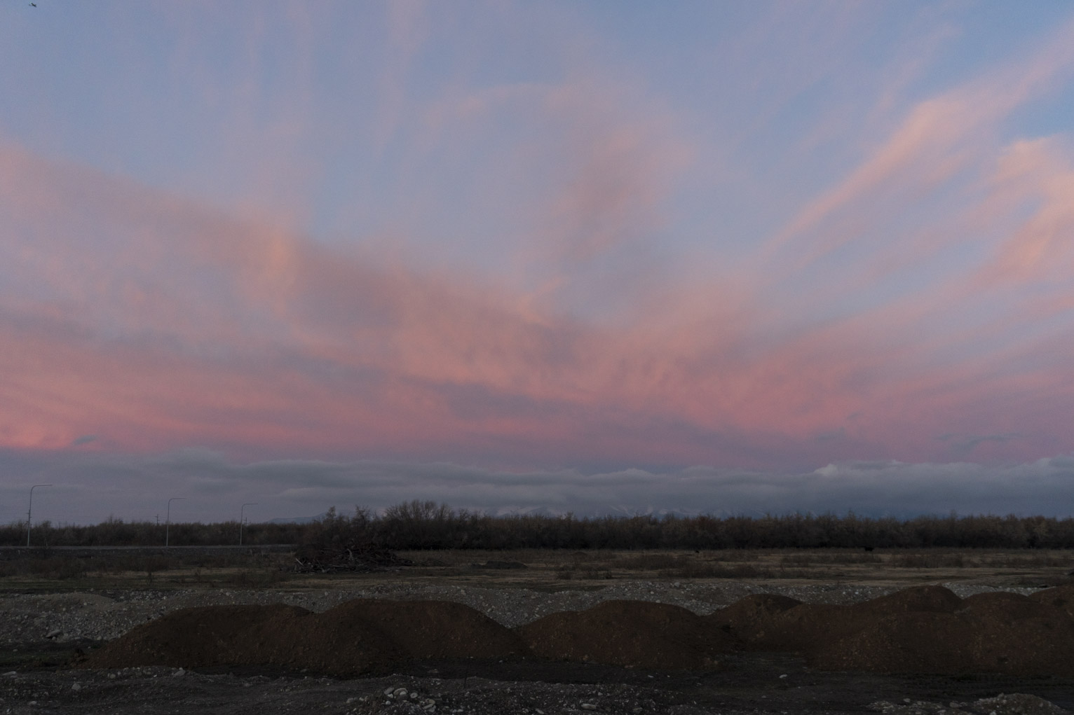 Above some dark piles sunlit streaky clouds